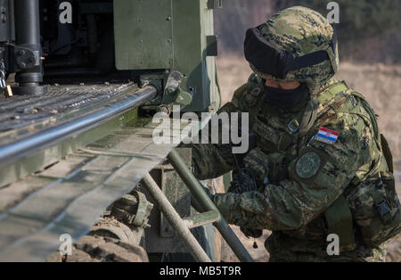 Un croato soldato di artiglieria assegnato al vulcano pacchi batteria lontano il suo equipaggiamento dopo aver eseguito una prontezza seminatrice con il suo team rocket sistema di artiglieria durante la partecipazione nel gruppo di combattimento della Polonia esercizio Puma a un intervallo vicino al Bemowo Piskie Area Formazione, Polonia, 22 febbraio, 2018. Questo soldato è una parte dell'esclusiva, multinazionale gruppo di combattimento composta di Stati Uniti, Regno Unito, croato e soldati rumeni che servono con il polacco della XV Brigata meccanizzata come una forza di dissuasione nel nord-est della Polonia a sostegno della NATO in avanti rafforzata presenza. Foto Stock