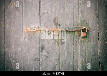 Porta bloccata. Chiuso il vecchio lucchetto arrugginito su un weathered porta di legno, primo piano Foto Stock