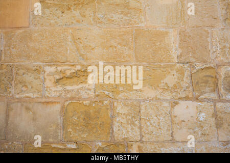 Weathered tradizionale muro di pietra calcarea facciata background in Malta Foto Stock