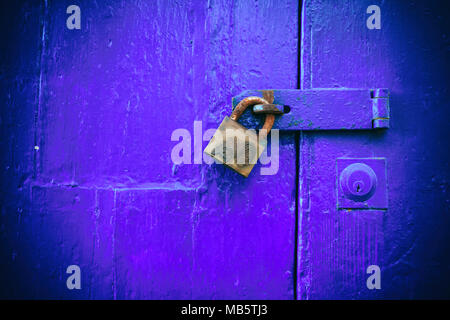 Porta bloccata. Chiuso il vecchio lucchetto arrugginito su un vecchio blu porta di legno, primo piano Foto Stock