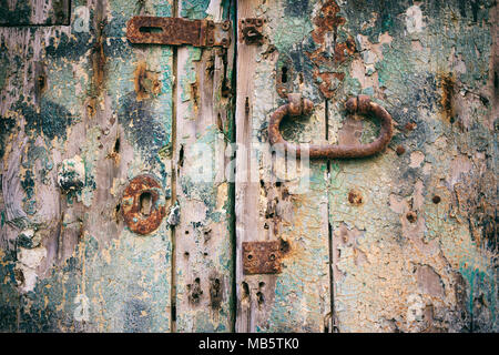 Addolorato dettaglio della porta. Chiuso vecchia porta di legno con serratura arrugginita e maniglia, primo piano Foto Stock