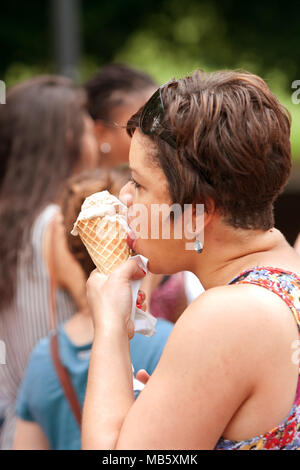 Una donna non identificato lambisce una cialda cono gelato al terzo annuale di Atlanta Gelato Festival a Piedmont Park, il 27 luglio 2013 ad Atlanta, GA. Foto Stock