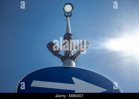 Tre telecamere di sorveglianza attaccato sulla luce led pole con l. Blu cielo con sunray come sfondo Foto Stock