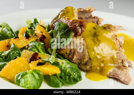 Gambe d'anatra con salsa di arancio e la valeriana con insalata di arance e aceto. Foto Stock