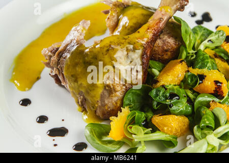 Gambe d'anatra con salsa di arancio e la valeriana con insalata di arance e aceto. Foto Stock