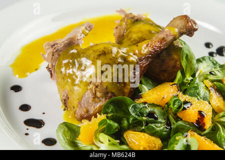 Gambe d'anatra con salsa di arancio e la valeriana con insalata di arance e aceto. Foto Stock