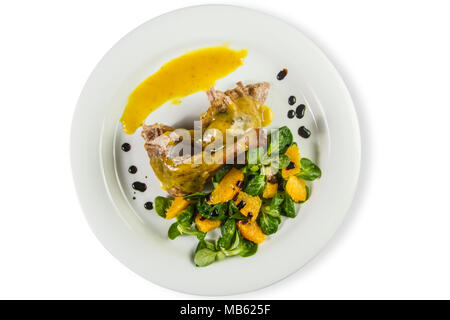 Gambe d'anatra con salsa di arancio e la valeriana con insalata di arance e vinegaron piastra bianca isolata su bianco. Foto Stock