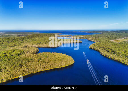 Due barche di scorrimento su superficie ancora di Myall lakes in NSW area costiera su una soleggiata giornata estiva con lontano oceano pacifico tra gumtree coperte Riva Foto Stock