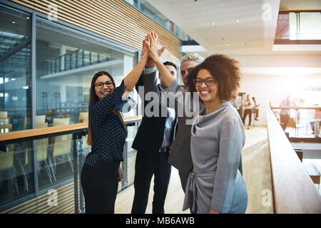 Sorridente in bianco e nero squadra in piedi e dando alta cinque tifo ogni altro in ufficio. Foto Stock