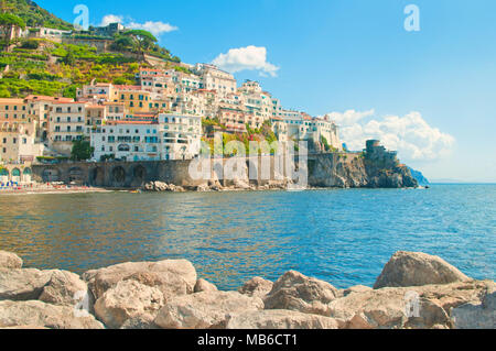 Bellissima vista della città di Amalfi con case colorate dal molo roccioso sulla soleggiata giornata estiva Foto Stock