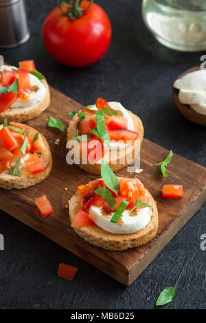 Italian bruschetta con pomodori a pezzi, basilico, mozzarella e aceto balsamico. Freschi Fatti in casa caprese bruschette o crostini e ingredienti Foto Stock