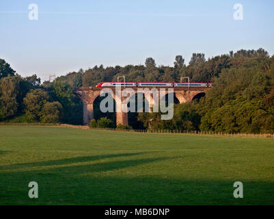 Un Virgin Trains treno pendolino attraversando il fiume Lowther viadotto sulla linea principale della costa occidentale vicino a Penrith Foto Stock