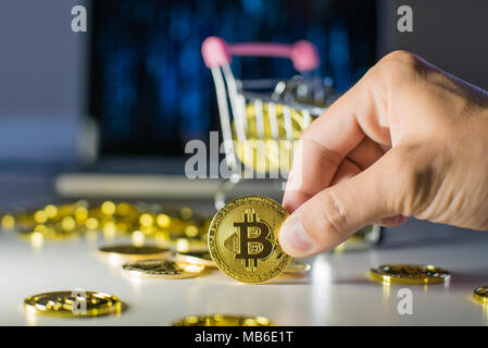 Bitcoin in mano. Tenere una moneta con le dita Foto Stock