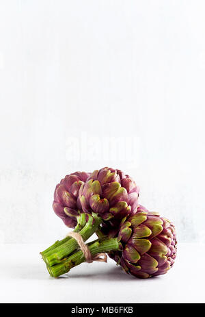 Nuovo mazzo di carciofi viola su sfondo bianco . molla cibo sano con spazio di copia Foto Stock