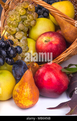 Mele e altri frutti in un cesto di vimini su uno sfondo bianco. Foto Stock