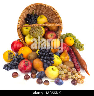 Mele e altri frutti in un cesto di vimini su uno sfondo bianco. Foto Stock