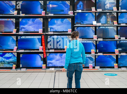 Donna che guarda i nuovi televisori ad alta definizione nel negozio elettrico