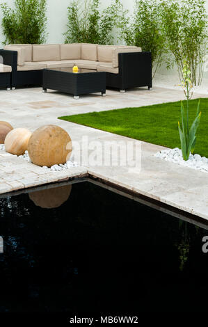 & Minimalista contemporaneo, "respirare" mostra giardino con patio elegante, area salotto, stagno & pietra sfere - RHS Flower Show, Tatton Park, Inghilterra, Regno Unito. Foto Stock