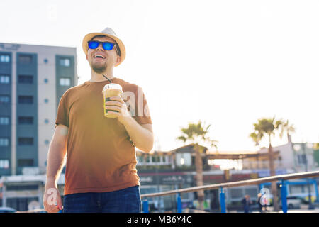 Lo stile di vita, le bevande e il concetto di persone - uomo in occhiali da sole di bere il caffè Frappé di carta usa e getta cup all'aperto Foto Stock