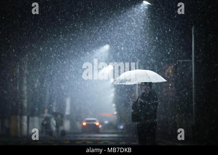 Pechino, Cina. 4 apr, 2018. Un uomo cammina nella neve a Nankai University di Tianjin, Cina del nord, 4 aprile 2018. Credito: Wang Xiaoming/Xinhua/Alamy Live News Foto Stock