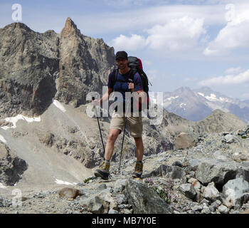 Tall atletico scalatore maschio sull'approccio escursione in remoto a un campo base in francese ASlps Foto Stock