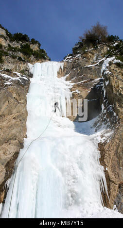 Maschio guida di montagna rappelling off una ripida cascata ghiacciata dopo una arrampicata su ghiaccio escursione Foto Stock