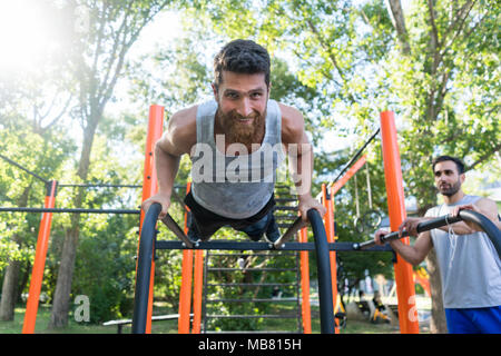 Atletica Giovane uomo facendo push-up durante l'allenamento all'aperto in un parco fitness Foto Stock