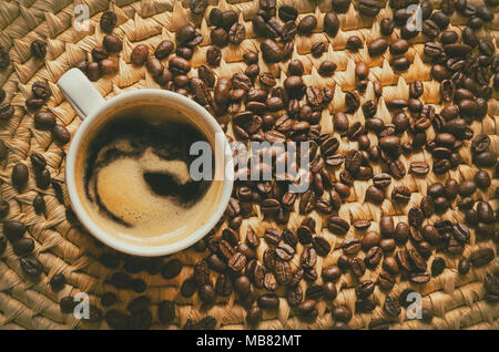 Vista superiore della tazza con caffè e chicchi di caffè espresso su un tessuto che serve il vassoio Foto Stock