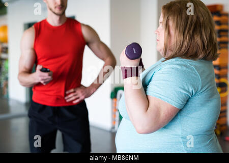 Donna obesa che lavora fuori con manubri Foto Stock