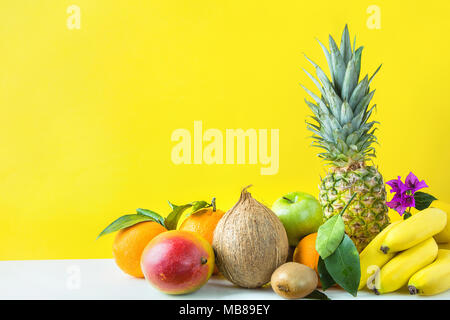 Composizione da un assortimento di differenti e tropicali Frutta estiva. Ananas Manghi Agrumi Noce di Cocco Arance Limoni Mele Kiwi banane disposti su Sto Foto Stock
