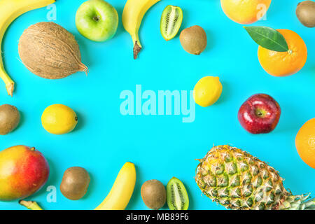Il telaio da diversi tropicale e stagionali estivi frutti. Ananas Manghi Agrumi Noce di Cocco Arance Limoni Mele Kiwi banane sparse sulla luce blu Ba Foto Stock