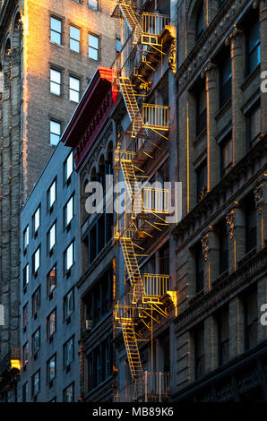 Luce calda del sole che splende su una via di fuga in caso di incendi sulla parte anteriore di un vecchio edificio nella città di New York Foto Stock