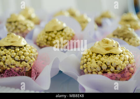 Cioccolato brigadeiro granulato con croccante di sfere e rabboccato con vernice dorata e un fiore di cioccolato sulla parte superiore. In una forma di caramelle. Chiudere la vista. Spazio di didascalia. Foto Stock