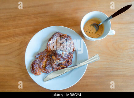 Croissant alle mandorle con caffè espresso, una rinomata prima colazione continentale Foto Stock