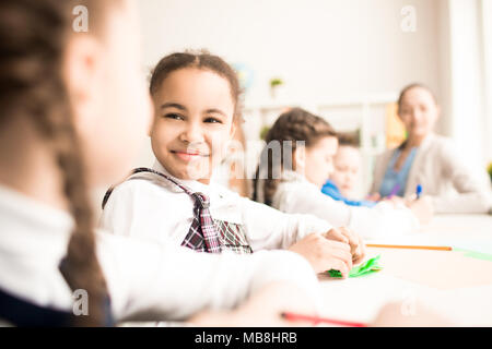 Schoolgirl comunicante con il suo compagno di classe durante una lezione Foto Stock