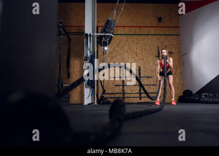 Immagine della donna sportiva in formazione con due funi in palestra Foto Stock