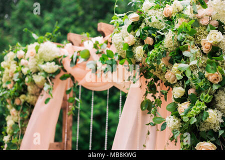 Bellissimo luogo reso con piazza di legno e rose floreali decorazioni per esterno cerimonia di matrimonio nel parco verde. Le impostazioni di nozze al luogo scenico. Hor Foto Stock