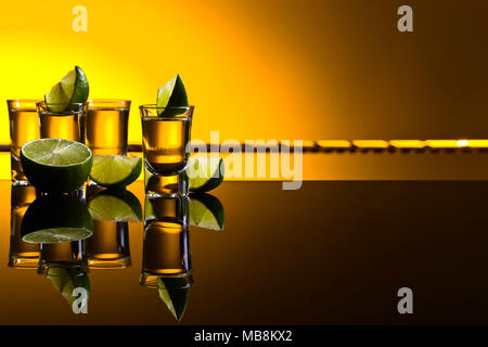 Mexican Gold Tequila in breve i bicchieri con calce su sfondo riflettente. Copyspace. Foto Stock