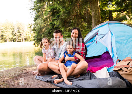 Giovane e bella famiglia con le figlie camping nella foresta. Foto Stock