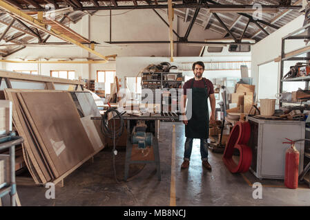 Giovane falegname in piedi da una panchina vide nella sua officina Foto Stock