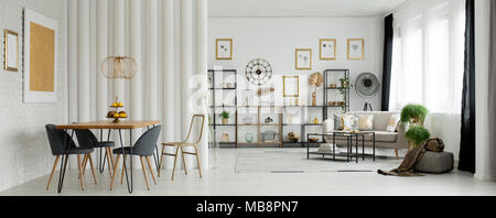 Oro dipinto su un bianco, muro di mattoni in open space soggiorno interno con un tavolo da pranzo in legno beige e il lettino Foto Stock