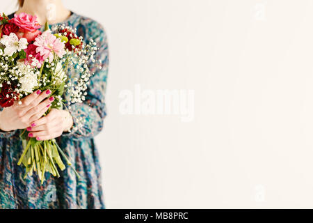 Donna con fiori di primavera in piedi contro uno sfondo bianco con spazio di copia Foto Stock