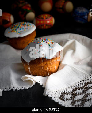 Pasqua tradizionale cottura dell'Ucraina con il bianco glassa di zucchero e un decor colorato su un asciugamano di tessili con pizzo, tavoli in legno nero Foto Stock