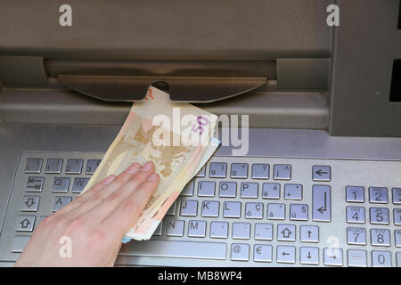 Mano che preleva il denaro delle banconote in euro da un bancomat di una banca europea Foto Stock