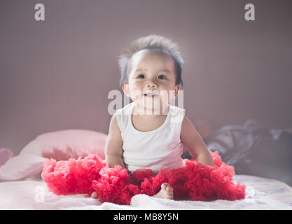 Asian new born baby sit e sorriso su un letto in camera da letto. Foto Stock