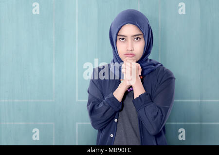 Allegro asian donna musulmana in hijab con gesto di mano su sfondo blu Foto Stock