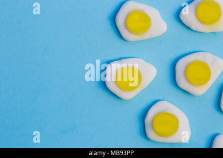 Uova fritte dolci caramelle overhead sul luminoso sfondo blu Foto Stock