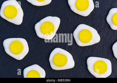 Uova fritte dolci caramelle overhead su sfondo scuro Foto Stock