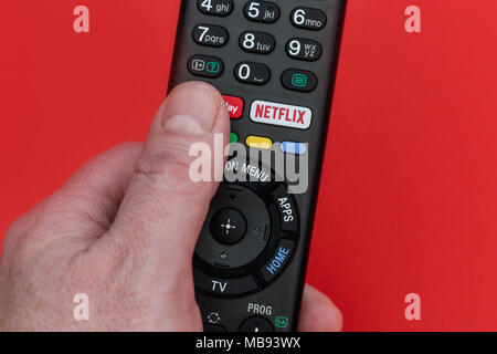 Londra - Aprile 06, 2018: la mano che tiene la televisione telecomando con pulsante di Netflix Foto Stock