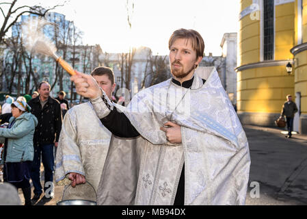 Kiev, Ucraina - 8 Aprile 2018: Sacerdote benedizione la gente allegra durante la Santa Pasqua Domenica cerimonia al di fuori di San Vladimiro's Cathedral di Kiev, Ucraina. Foto Stock